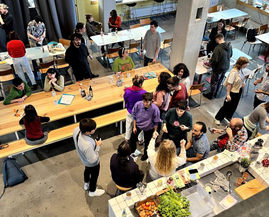 A group of people having food and drinks in the cafe area of Impact Hub Berlin